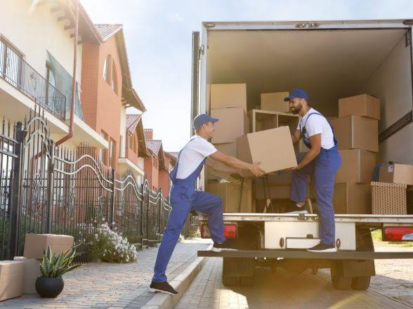 Movers loading boxes into truck on residential street